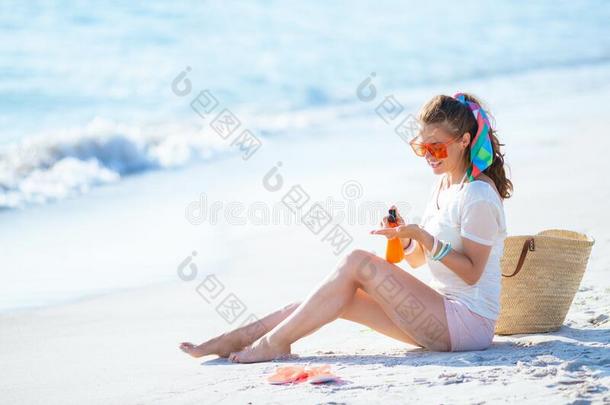 微笑的女人应用太阳块在期间一次向海岸