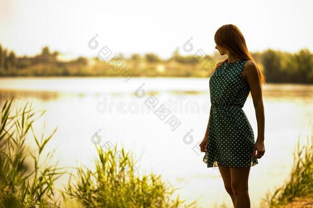 年幼的女人起立和享有夏一天和湖在后面