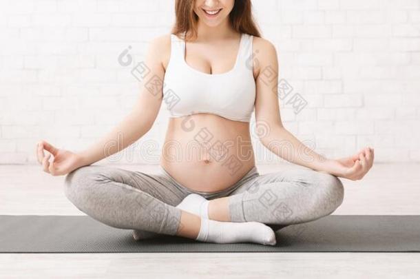 积极的怀孕的女人深思采用莲花位置在家