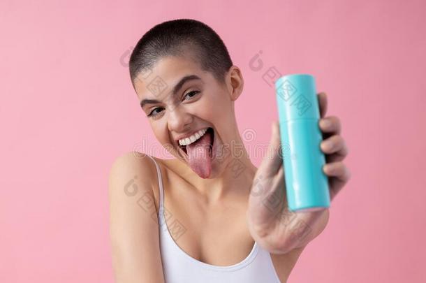 有趣的女士展映她舌头和化妆品瓶子股份照片