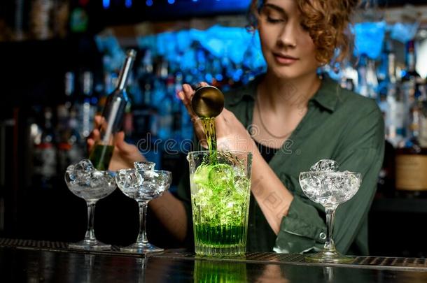 年幼的女人酒吧间销售酒精饮料的人活跃地涌出绿色的喝进入中大大地glasnost开放