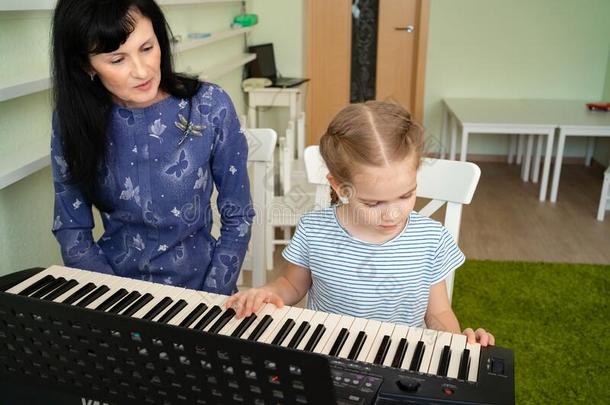 教师教小的女孩向比赛向键盘.