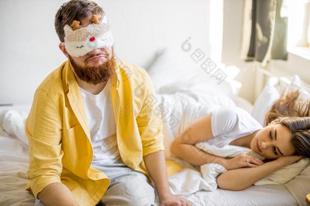欲睡的男人坐向床在近处睡眠妻子