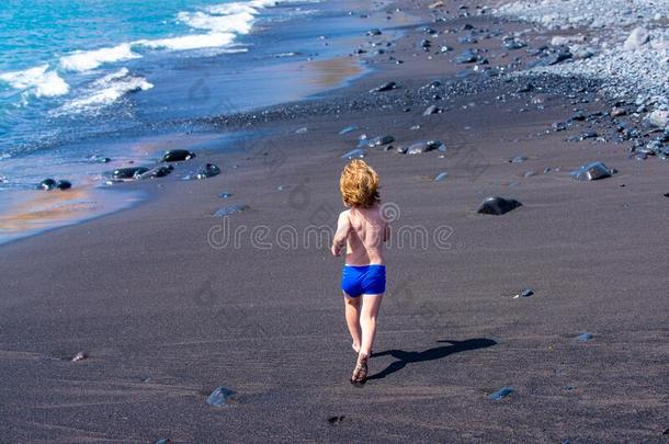 慢跑向指已提到的人海滩.运动员的男孩跑向指已提到的人黑的沙在近处英语字母表的第20个字母