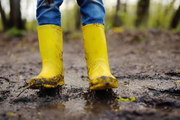 淘气的学龄前儿童小孩使人疲乏的黄色的雨擦靴人用于跳跃的