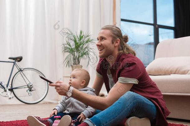 幸福的父亲观察television电视机和他的小的儿子
