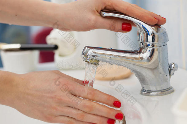 女人洗涤手在下面流动的轻敲水采用指已提到的人浴室