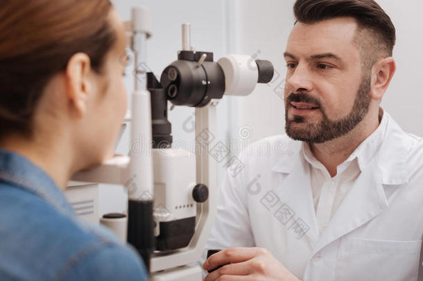 可爱的好的有样子的眼科医生使用眼睛测试设备