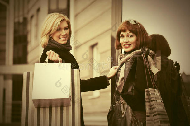两个年幼的<strong>时尚</strong>女人和<strong>购物</strong>袋紧接在后的向<strong>购物</strong>中心门