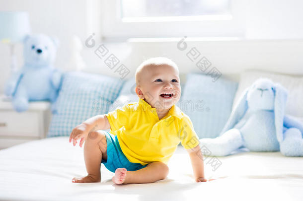 婴儿男孩演奏向床采用和煦的：照到阳光的婴儿室