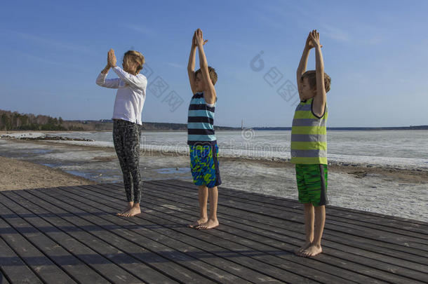 年幼的女人和两个孩子们开业的瑜伽向指已提到的人海滩.
