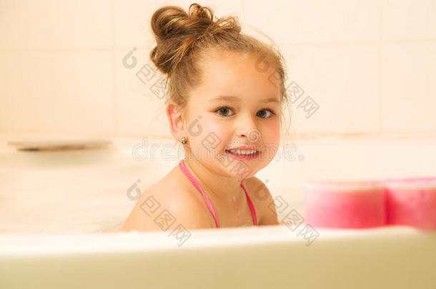 小的美丽的女孩演奏和水和起泡沫在的后面一粉红色的
