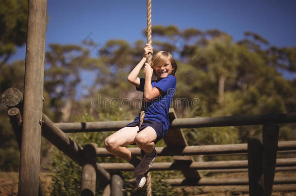肖像关于微笑的女孩攀登的粗绳在的时候障碍课程
