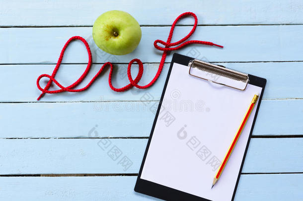 观念日常饮食,绿色的苹果和有纸夹的笔记板和日常饮食字母表.