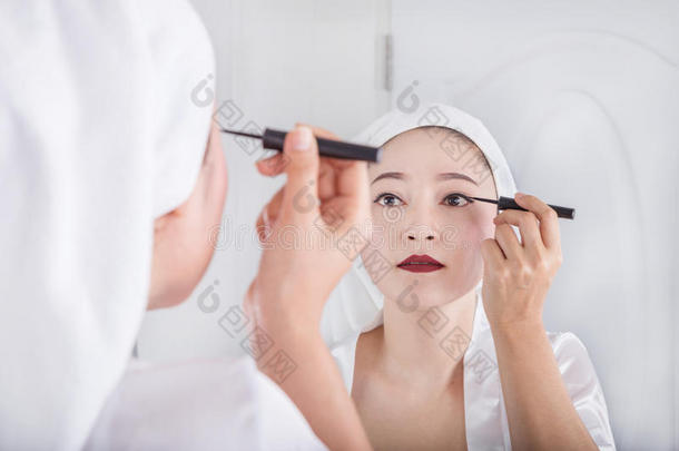 女人有样子的镜子和做-在上面和黑的眼线膏