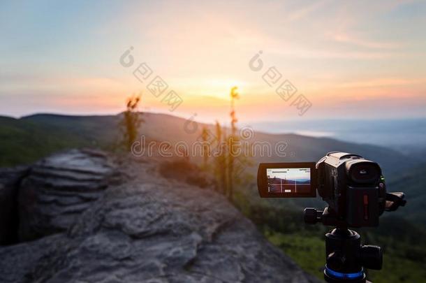 数字的磁带录像照相机向三脚架拍摄电影日出在山.
