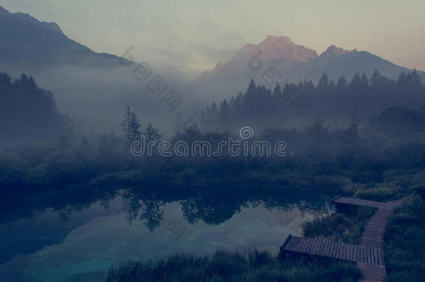 早晨薄雾上升的在上面湖被环绕着的在旁边山.