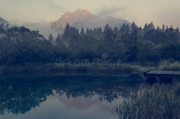 早晨薄雾上升的在上面湖被环绕着的在旁边山.