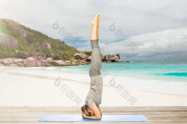 女人做<strong>瑜伽</strong>采用头手<strong>倒立</strong>使摆姿势向海滩