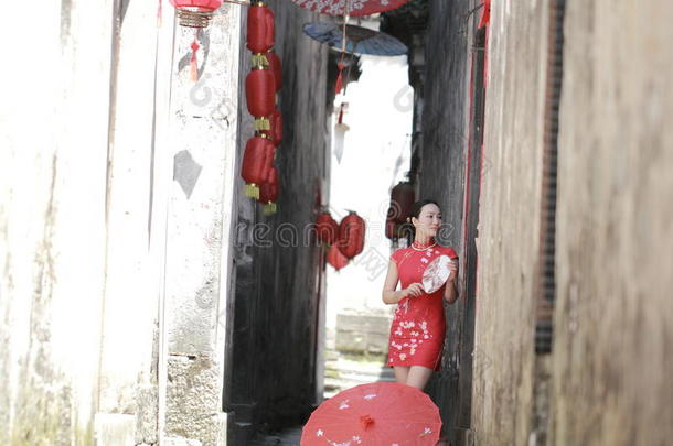 幸福的<strong>中国</strong>人女人采用红色的旗袍走采用指已提到的人胡同