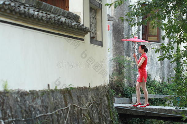 幸福的中国人女人采用红色的旗袍旅行在古代的城镇