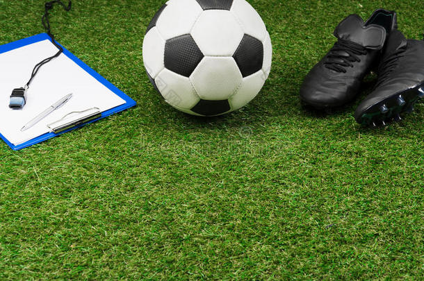 有纸夹的笔记板和足球球和擦靴人向草场地