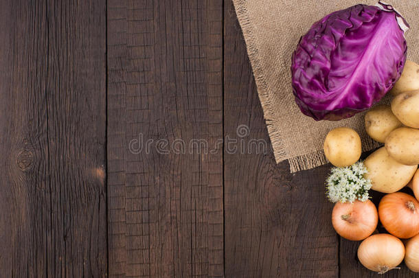紫色的甘蓝,马铃薯和洋葱向一老的黑暗的木材表.