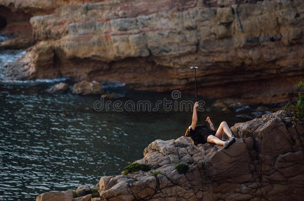 女人做自拍照使用自拍照粘贴.年幼的女孩谎言向一岩石