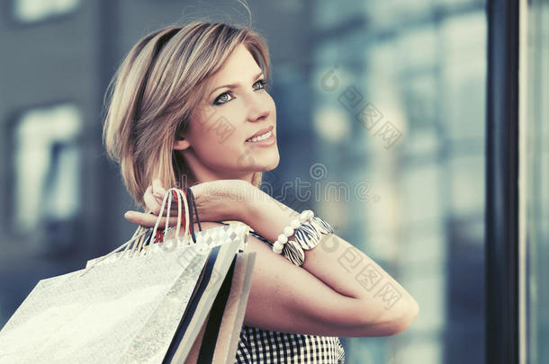 幸福的年幼的时尚女人和购物袋步行采用指已提到的人购物中心