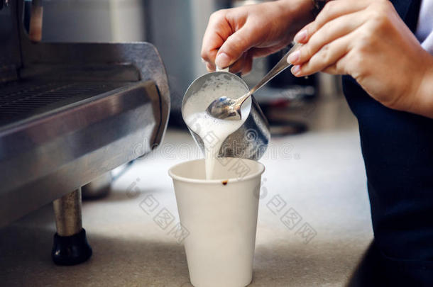 咖啡馆准备咖啡的<strong>员工</strong>传布热的奶采用咖啡豆纸杯子.
