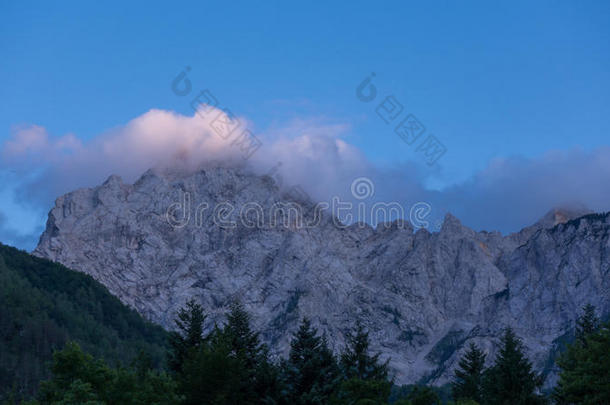 阿尔卑斯山的山山峰采用日落向蓝色天,云和森林采用