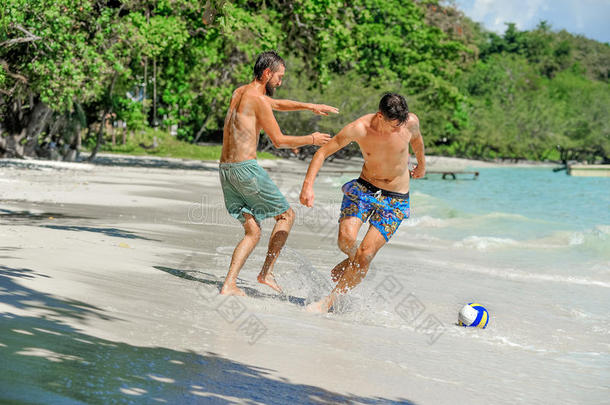 朋友演奏足球在指已提到的人和煦的：照到阳光的热带的海滩