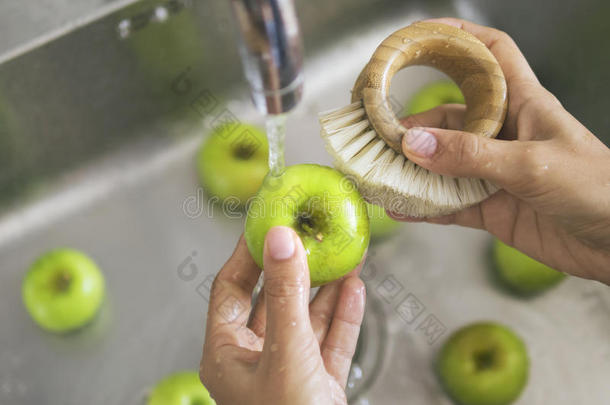 年幼的严格的素食主义者女孩洗涤绿色的苹果和竹子刷子.手int.引人注意