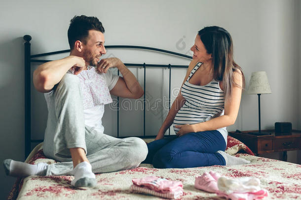 男人展映婴儿衣服向怀孕的女人