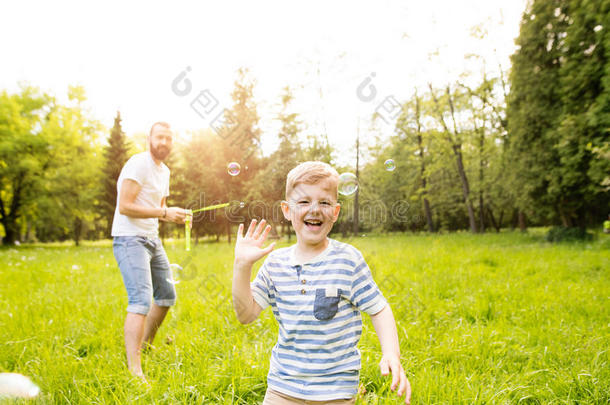 低到臀部的父亲和儿子吹风泡在户外采用公园.
