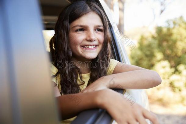 年幼的女孩微笑的和有样子的出局关于敞开的汽车窗