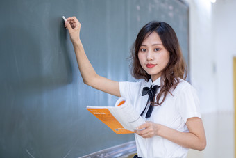 黑板前拿粉笔写字的女生