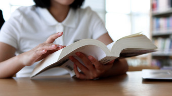 图书馆<strong>看书</strong>的女大学生学习阅读书写作业