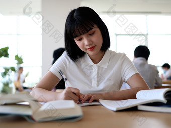 图书馆看书的女大学生学习阅读书写作业