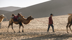 敦煌沙漠牵着骆驼的人