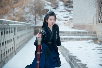 雪天古城身穿汉服扮演武侠的中国少女