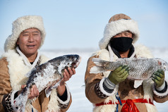 寒冷的冬季在冰冻的湖面上凿冰捕鱼的人们