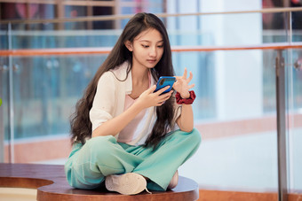 假日在商场休息区用手机自拍的中国少女