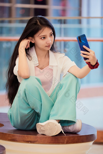 假日在商场<strong>休息区</strong>用手机自拍的中国少女