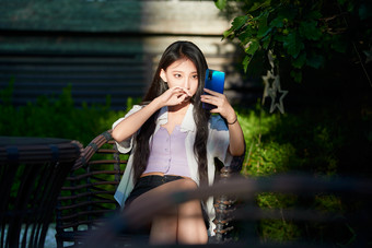 <strong>夕阳</strong>下在庭院休息拍照的亚洲少女