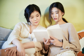 坐在床上读书的俩位美女