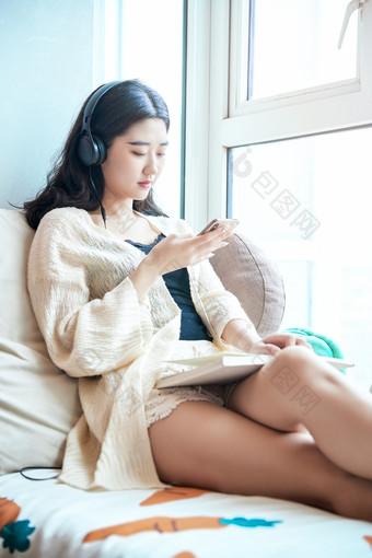 躺在舒适的飘窗上听音乐看书玩手机的女孩