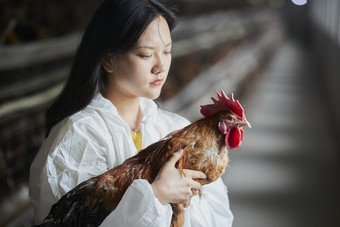 身穿防护服怀抱家禽的年轻女性饲养员