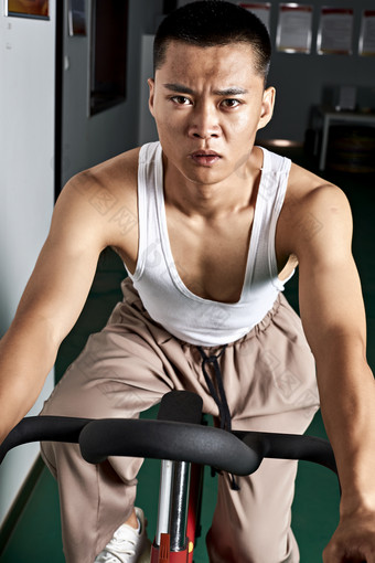 在室内进行动感单车锻炼的亚洲健身男士形象
