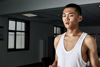 在室内用<strong>跑步机</strong>进行锻炼的亚洲健身男士形象